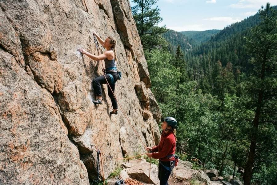 A climber on a rock face with a belayer below